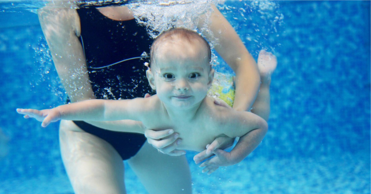 Baby unter Wasser wird von Mutter gehalten