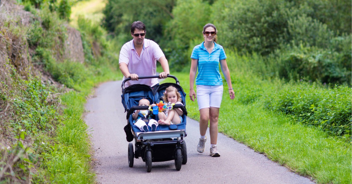 Familie wandert mit Zwillingskinderwagen