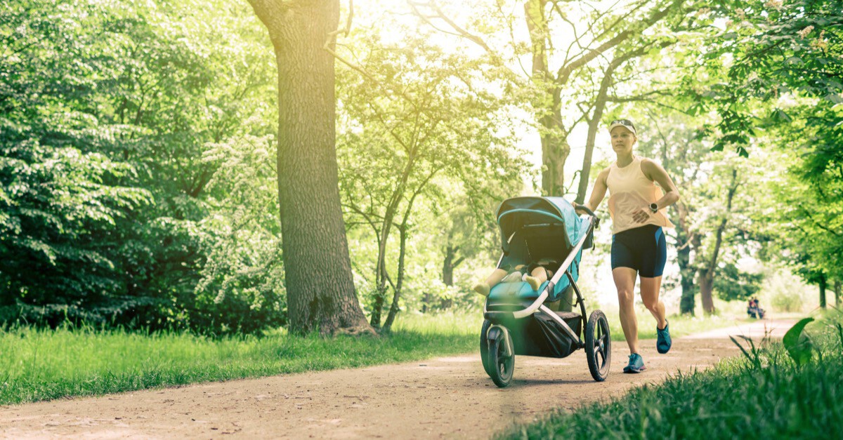 Frau joggt mit Kinderwagen in Park