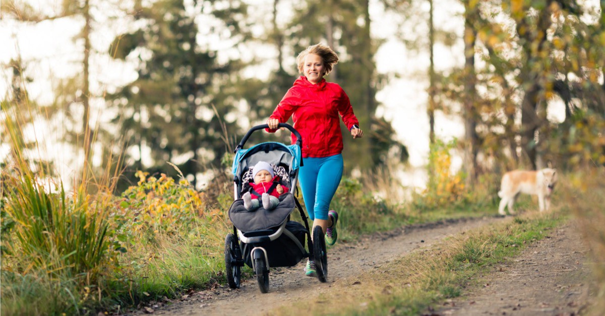 Frau läuft mit Kinderwagen im Wald