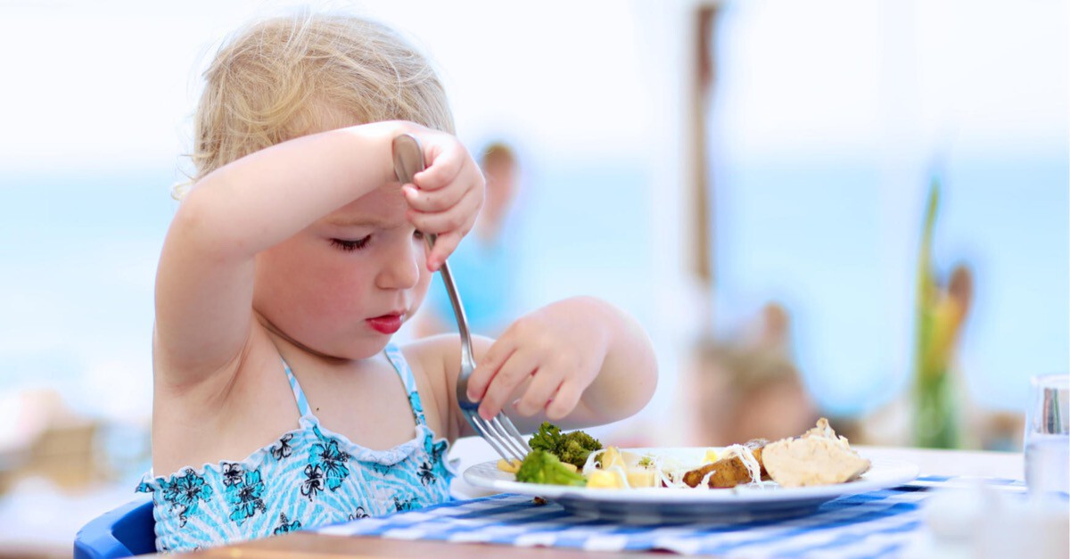 kleines Mädchen isst am Strand