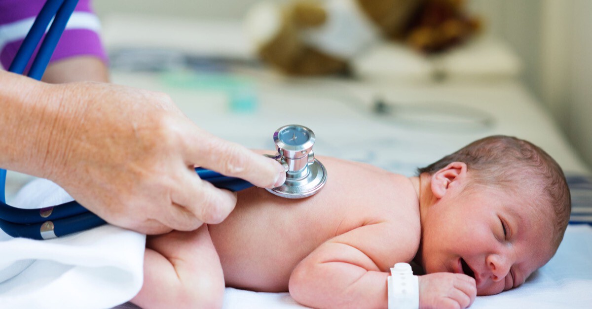 Neugeborenes wird mit Stethoskop untersucht