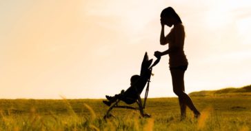 Mutter mit Kinderwagen hält sich Hand an den Kopf