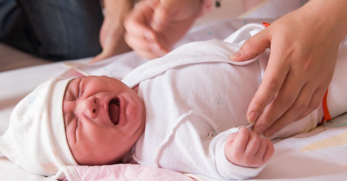 schreiendes Baby um das sich Eltern kümmern