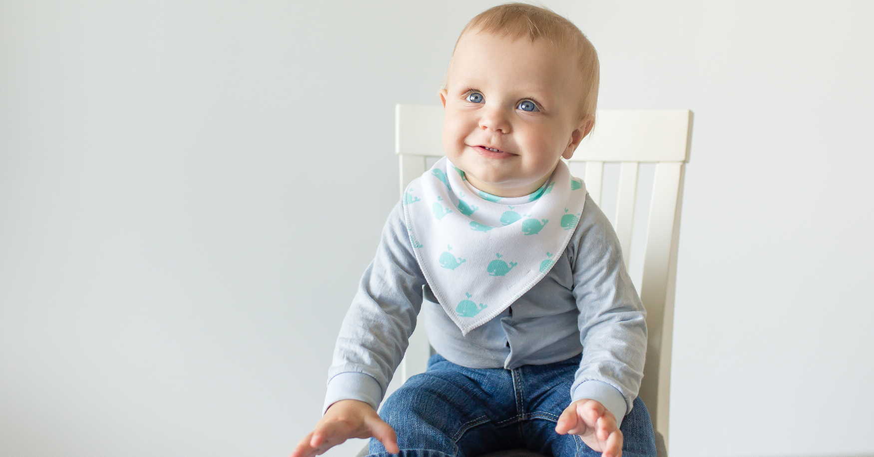 Baby mit Lätzchen sitzt auf Hochstuhl