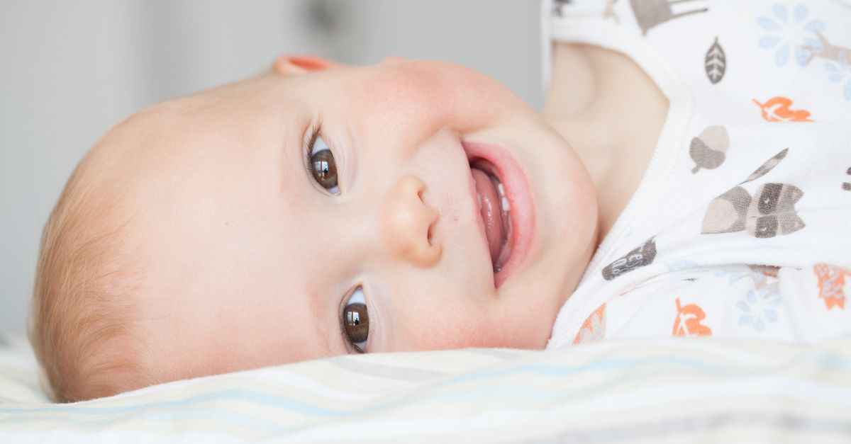 Baby liegt auf der Seite zeigt Zähne