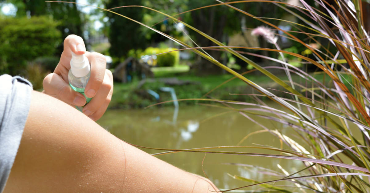 Frau verwendet Insektenschutzspray bei Teich